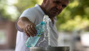 Луѓе се разладуваат на улица под ладовина и со шишиња вода за време на екстремно топло време.