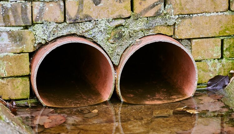 Sewers with toxic dirty water from metal pipes. Draining water from city sewer. Environmental pollutionc